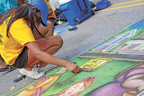 Lovepreet Kaur puts the finishing touches on Grand Island's chalk mural at the Chalk Walk competition.