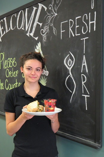 Carly Farruggia holds the bacon breakfast sandwich and a side of fruit.