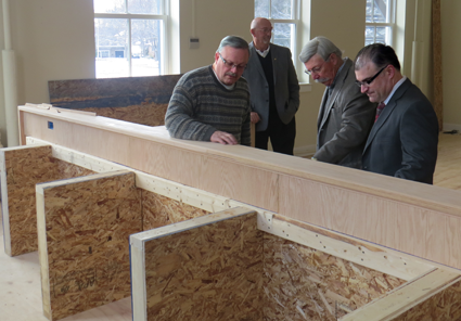 Trustee Vic Eydt, left, explains the wood carving on the new village dais to Mayor Terry Collesano and Engineer Mike Marino.