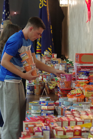 Tom Stedman of the Grand Island boys varsity soccer team sorts food donated by fellow Islanders for others in need.