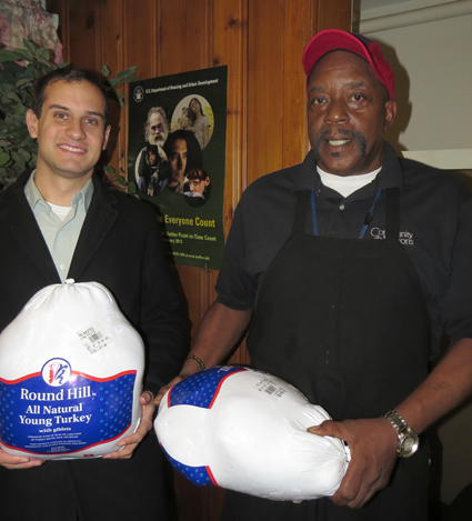 Community Missions Communications and Development Manager Christian Hoffman, left, holds one of the Thanksgiving turkeys chef Jimmie Walker will prepare for guests this holiday season.