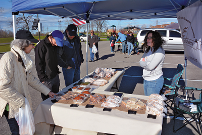 Visitors browse baked goods from Rise Up Breads & Bakery.