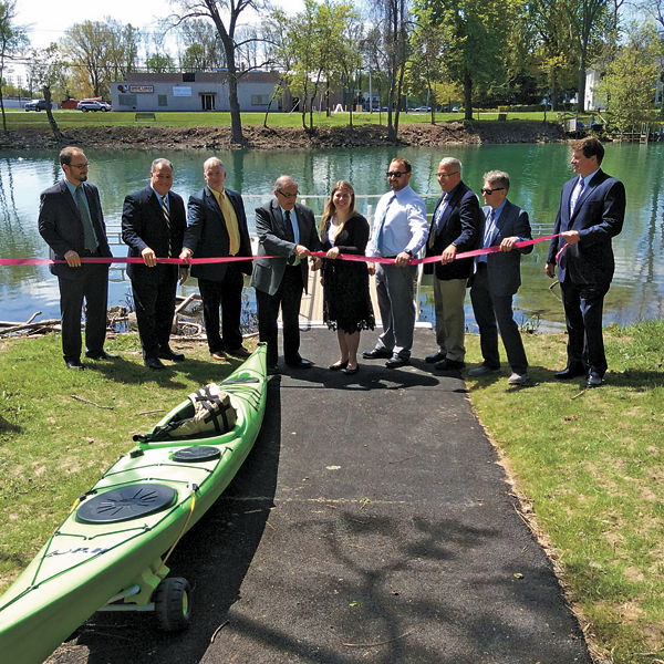 City officials surround North Tonawanda Mayor Arthur G. Pappas (center) as he cuts the ribbon for the city's new bike extension and kayak launches.