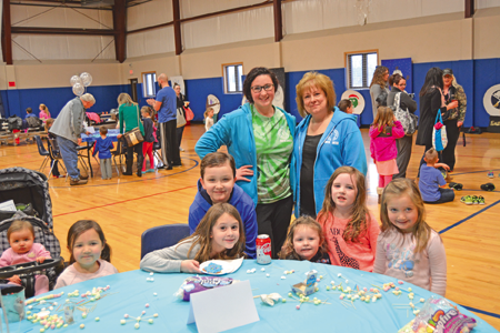 You Center Administrative Assistant Debbie Reed (standing, at right) and Olivia Toner pose for a photo with children at one of the children's activities stations. (Photo by Lauren Zaepfel)