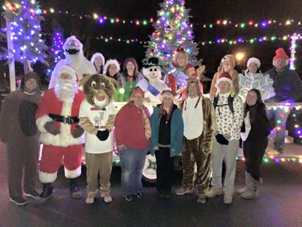 Volunteers dressed up as holiday characters in front of the trailer enjoy a fun night of caroling. (Photo by Martha Russell)