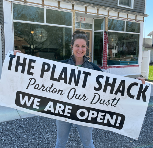 Rachel Stepien holds up a sign signaling The Plant Shack is open for business.