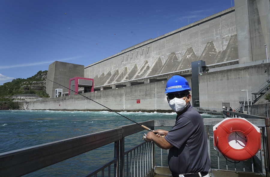 A masked Gil C. Quiniones, NYPA president and CEO, casts his fishing line off the Niagara Power Project's fishing pier during a recent visit to the project. (Photo: Niagara Fishing Pier, credit: NYPA)