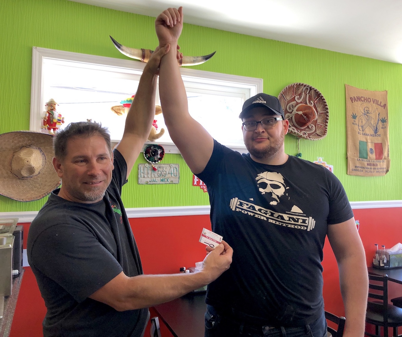 Spicey Pickle owner Aaron Rotella holds up the hand of new taco-eating contest winner Colton Keen.