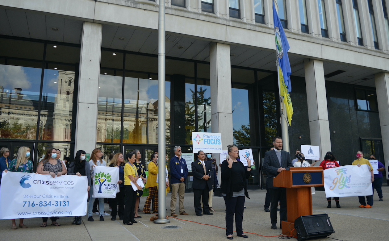 Rev. Roger Griffiths of Zion Lutheran Church (at podium) sings `You Raise Me Up` as a yellow Flag of Hope is raised at the Edward A. Rath county office building in downtown Buffalo.