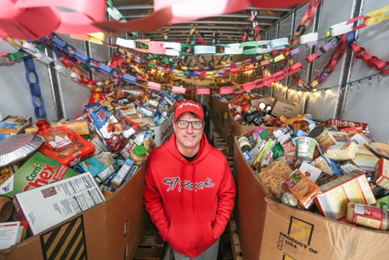 DJ Jickster in a FeedMore WNY trailer surrounded by food donations at `Rock Out Hunger.` (Photo credit: Joe Cascio/courtesy of FeedMore.) 