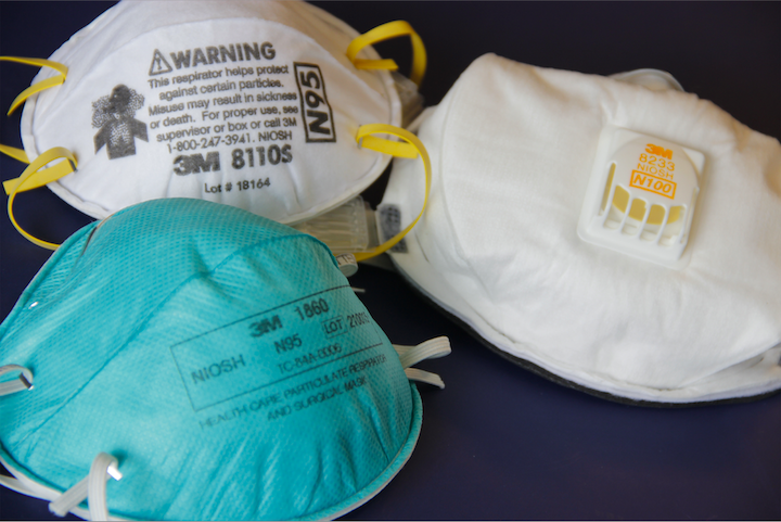 This image depicts a still life composed of two N95-type face masks, or respirators, at left, one turquoise (foreground), the other white. On the right, you'll note a third respirator, a N100-type mask. The N95 respirator works as an air-purifying respirator (APR), also known as a filtering face piece respirator, and is certified by the National Institute for Occupational Safety and Health (NIOSH). The N95 is designed to protect against particulate matter such as dust, fumes, mists, aerosols and smoke, as well as biological particles, including pollen, mold spores, bacteria, viruses, animal dander and allergens. It is also able to filter aerosolized droplets, in particular, smaller droplets which evaporate to form droplet nuclei. (Photo by Debora Cartagena/courtesy of the U.S. Centers for Disease Control and Prevention)