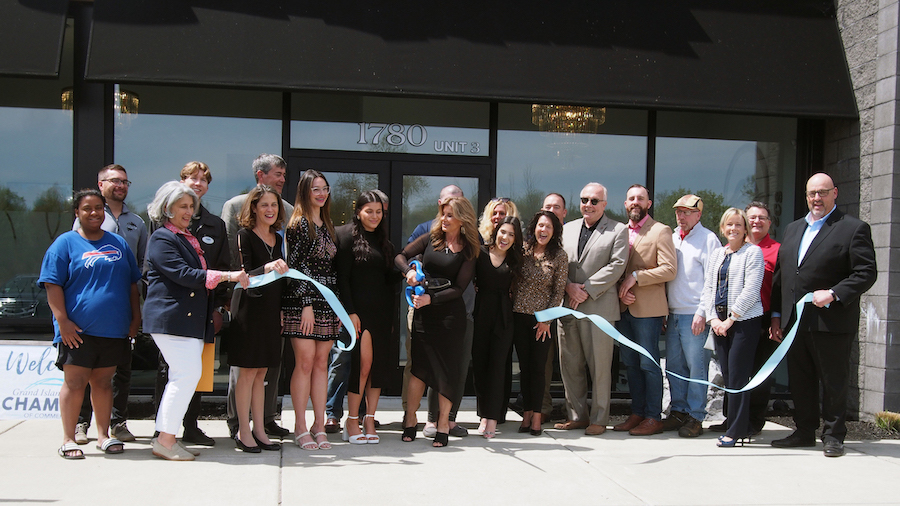 Karen Paolini cuts the ribbon at Island Aesthetics, as coworkers, town officials and members of the Grand Island Chamber of Commerce watch.