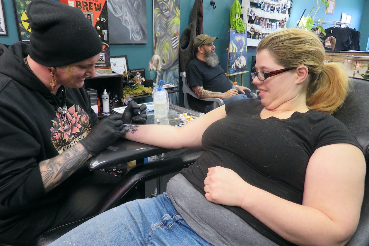Daniel Black works on a tattoo for Chelsea, who said she was getting her first tattoo.