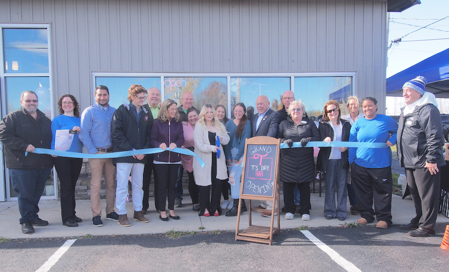 Theresa West, owner of T's Dry Bar, cuts the ribbon to celebrate her business. She is surrounded by government officials and members of the Grand Island Chamber of Commerce.