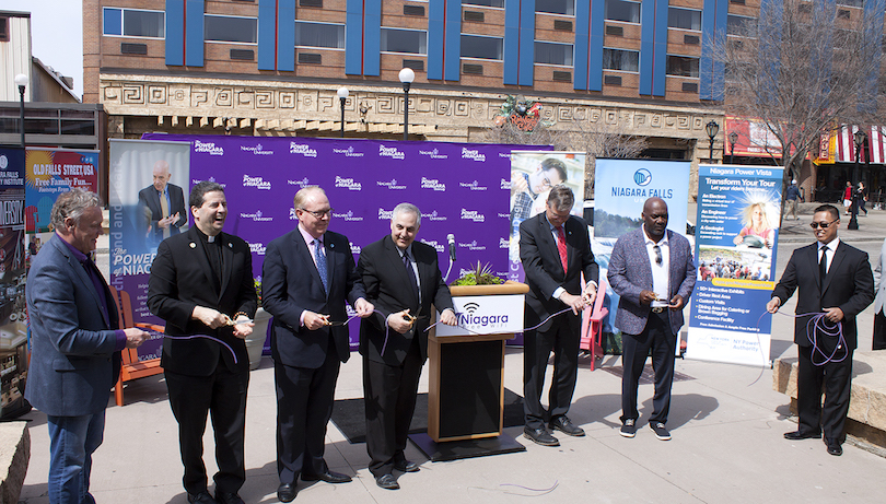 A symbolic cutting of the Ethernet cord took place Friday in Niagara Falls as officials announced details of complimentary wireless internet service in the downtown corridor. Pictured, from left, are Patrick J. Whalen, director of Niagara University's Niagara Global Tourism Institute; Rev. James J. Maher, C.M., president of NU; John Percy, president and CEO of Destination Niagara USA; Lou Paonessa, community affairs director for the New York Power Authority; Niagara Falls Mayor Paul Dyster; Thurman Thomas, 34 Group president; and Roscoe Naguit, assistant director of the NGTI.