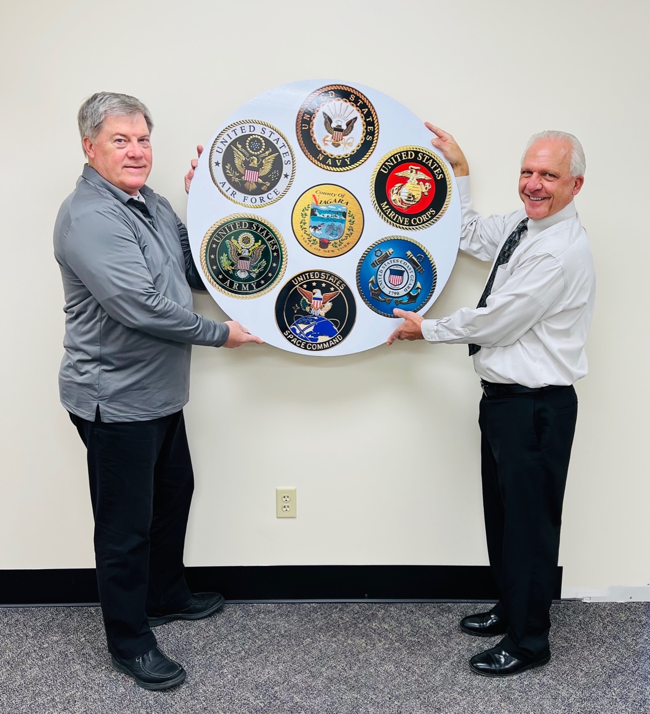 Niagara County Veterans' Service Agency Director Jeff Glatz and Niagara County Clerk Joseph A. Jastrzemski hang the sign for the agency at its new location in the Niagara County Courthouse, 175 Hawley St., Lockport.