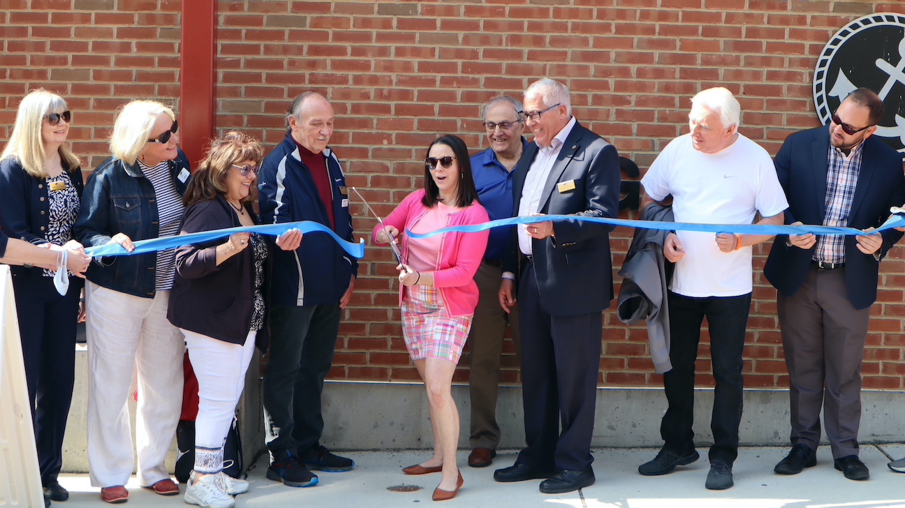 Laura K. Bernsohn, Gateway Cities Promotions Committee cuts the ribbon for the new Visitors Center of the Tonawandas located in Gateway Harbor Park as members of the Chamber of Commerce of the Tonawandas, city officials from both Tonawanda and North Tonawanda, and others look on.