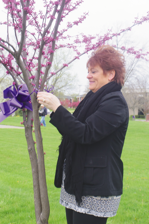 A woman ties a purple ribbon around a tree at a past Grand Island Relay For Life `Paint the Town Purple Day.` (Submitted photo)