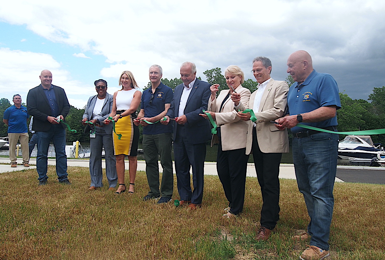 Elected officials, as well as representatives from State Parks, use multiple pairs of scissors to cut a ribbon.