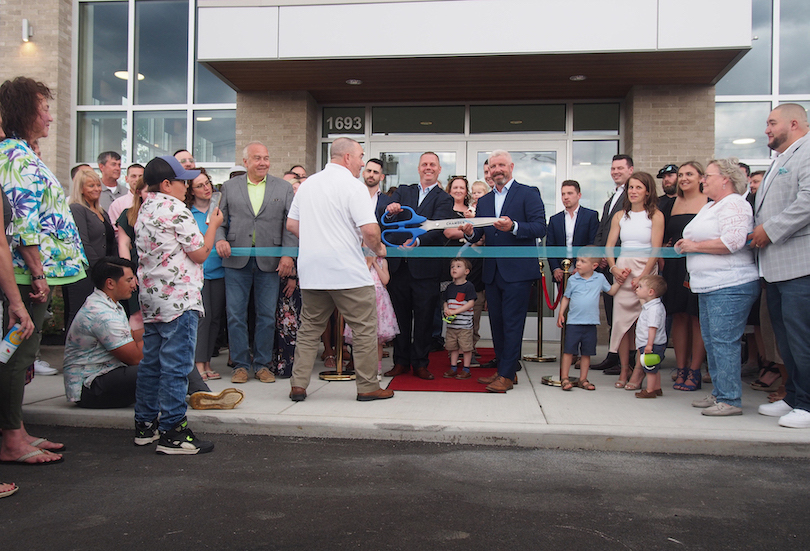 Chamber of Commerce President Eric Fiebelkorn presents the scissors for the ribbon cutting to certified AutoBrokers' co-owners Travis Smith and Chris Taylor.