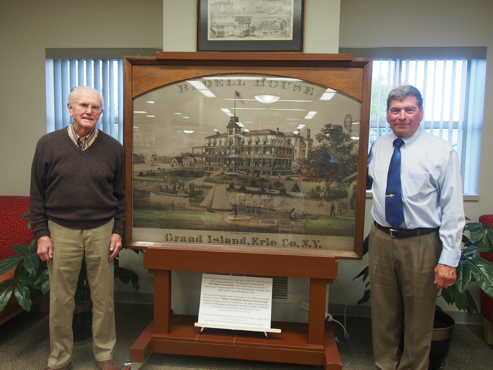 Jack Bedell and Curt Nestark with the Bedell House lithograph at the Grand Island Memorial Library, where it is being displayed.