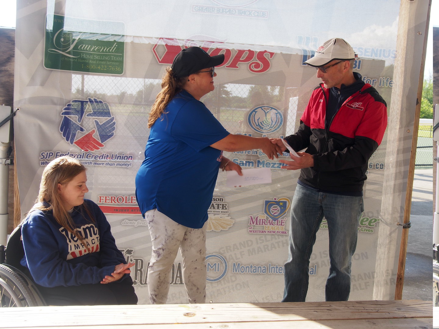 Brian McElroy, race director for the Grand Island Half Marathon, presents a donation of $5,000 to Coach Gale of the Miracle League of Western New York as a player looks on.