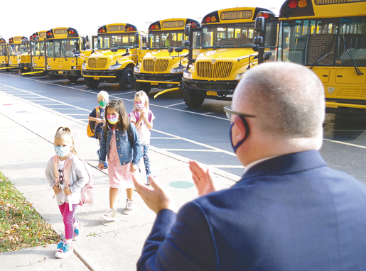 Grand Island Superintendent of Schools Brian Graham applauds as Sidway Elementary School students exit the buses in the morning and enter the building for the first day of school Wednesday. (Photo by Larry Austin)