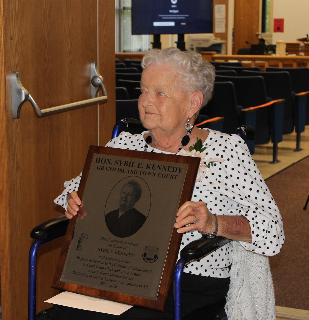Former Town Justice Sybil E. Kennedy holds a plaque outside the Grand Island Town Courtroom that has been dedicated in her honor. (Photo by Karen Carr Keefe)