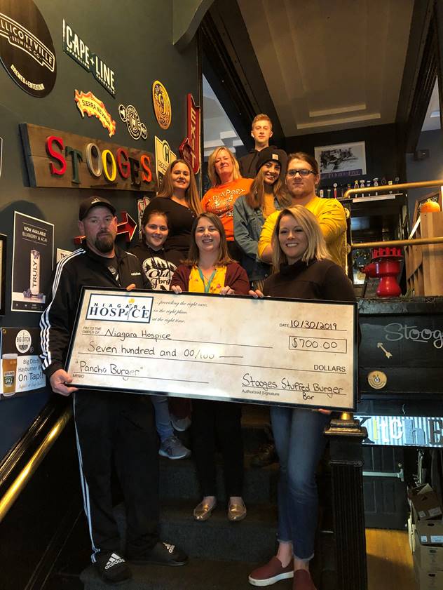 Stooges Stuffed Burger Bar owners Joe Blaszczak and Adrienne Kuzma (front row, left and right) and their staff present ceremonial check for $700 from the proceeds of the sale of their specialty `Pancho Burger` to Niagara Hospice Special Events Coordinator Allison Bolt (front row, center, front row).