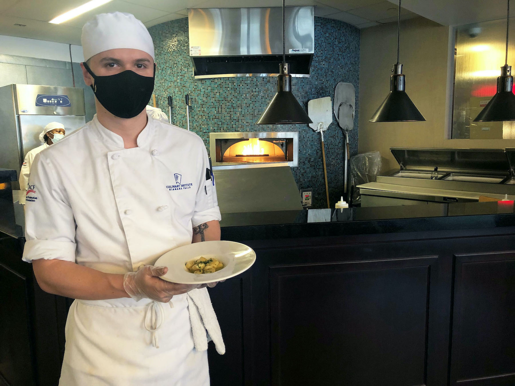 Student chef Sean Jones shows off a plate of housemade ricotta gnocchi from the Savor dinner menu.