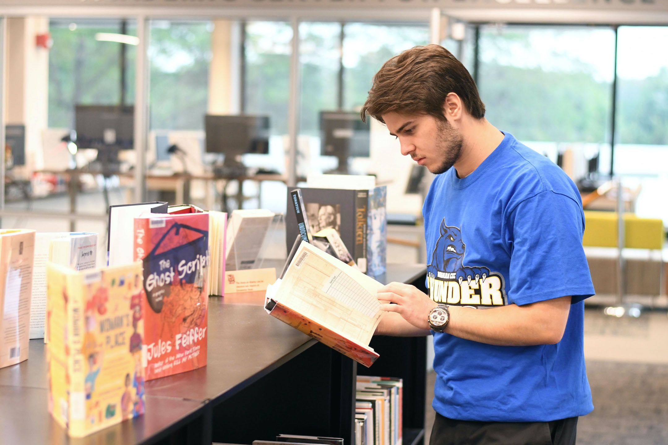 NCCC alumnus Matthew Archambault reads through the new releases available at the Lewis Library.