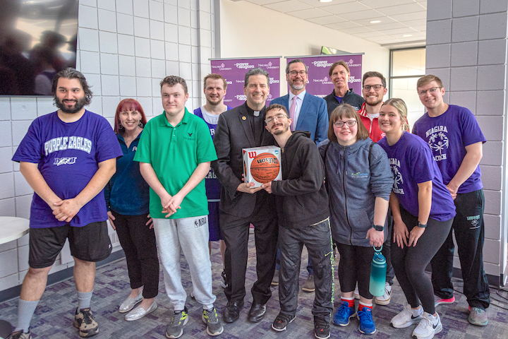 Special Olympians with the Rev. James J. Maher, C.M., president, Niagara University (center), and other presenters after the announcement of the return of the Special Olympics New York's Western Regional Basketball Tournament to the Niagara University campus. Speakers included Dr. Dennis Garland, associate professor of special education; Mike Paglicci, associate director, programs, Western Region, Special Olympics New York; Stan Wojton, principal, Cataract Elementary School; Beth Duncan, senior day supervisor, People, Inc.; and NU students Ella Juron, College of Education, and Robert Harrington, College of Hospitality, Sports, and Tourism Management.