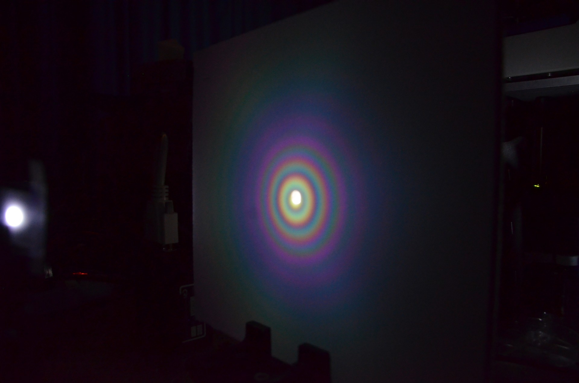Concentric rainbows are produced when white light is reflected by microscale concave interfaces. This image shows the experimental set-up. (Credit: Jacob Rada)