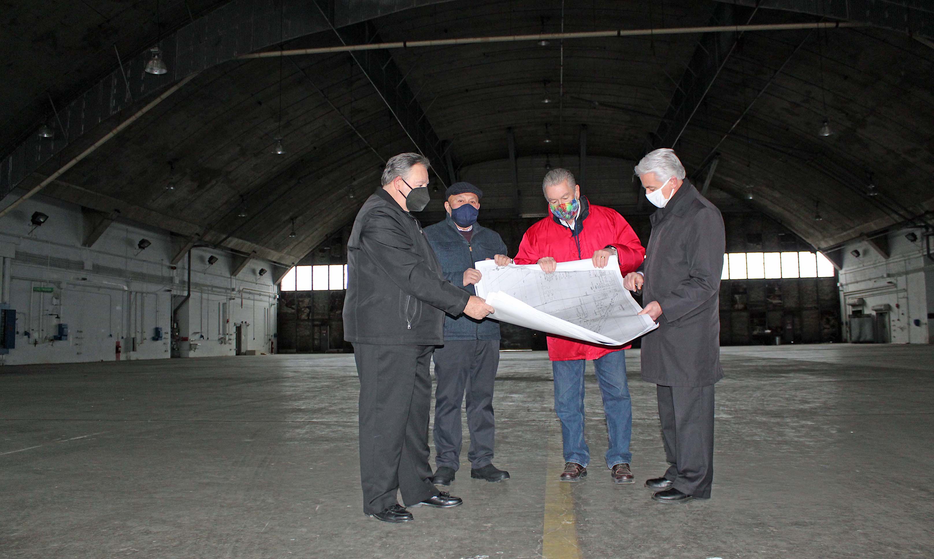 Pictured, from left: Town of Niagara Supervisor Lee Wallace, Assemblyman Angelo Morinello, John R. Simon and Niagara Falls Mayor Robert Restaino, in the 47,000-square-foot hangar, review the facility blue print.
