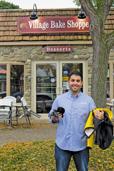 Mike Fiore stands in front of the Village Bake Shoppe with coats, hat and gloves in hand. His bakery is accepting new and gently used winter clothing items, which will be donated to Community Missions.