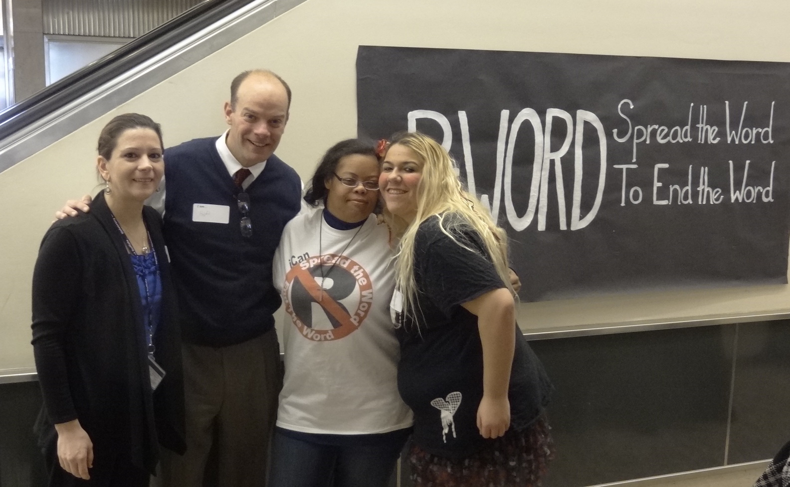 Executive Director of the Erie County Office for the Disabled Frank Cammarata (center, with nametag) is joined by Brie Kishel of the UB Alberti Center (left) and members of the iCan Clothing Co. and Unique Productions at Friday's community forum to `Spread the Word to End the Word.`