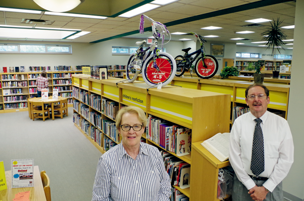 Children's Librarian Anne Slater and Memorial Library Director Lynn Konovitz are pictured with the boys and girls bikes up for grabs this summer as part of a Grand Island Memorial Library raffle. (Photo by Larry Austin)