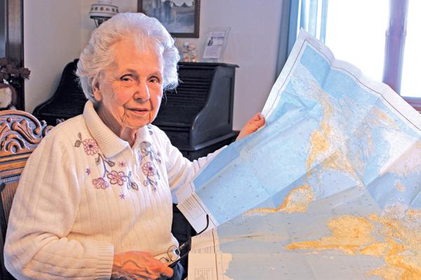 Shirley Kreger Luther looks over one of the world maps she and her staff used to track the locations of the servicemen and women they mailed the Islander newspaper to during World War II. (Photo by Karen Carr Keefe)
