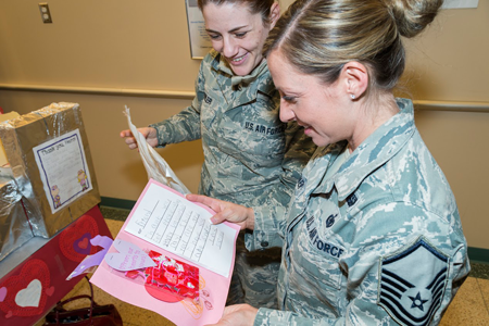 Master Sgt. Brandy Fowler (107th Public Affairs, left) and Master Sgt. Krystal Stegner (107th Recruiting and Retention) read through Valentine's Day cards.