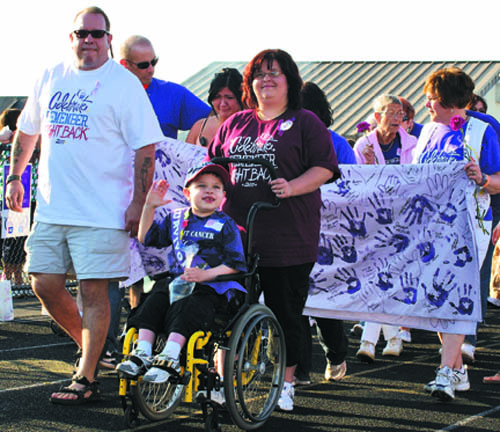Ian Cameron, the 2011 honorary survivor for the Grand Island Relay For Life, waves to the crowd during the survivors lap during the event on June 3. He is made the lap with his parents, Dona and Robert Cameron. 