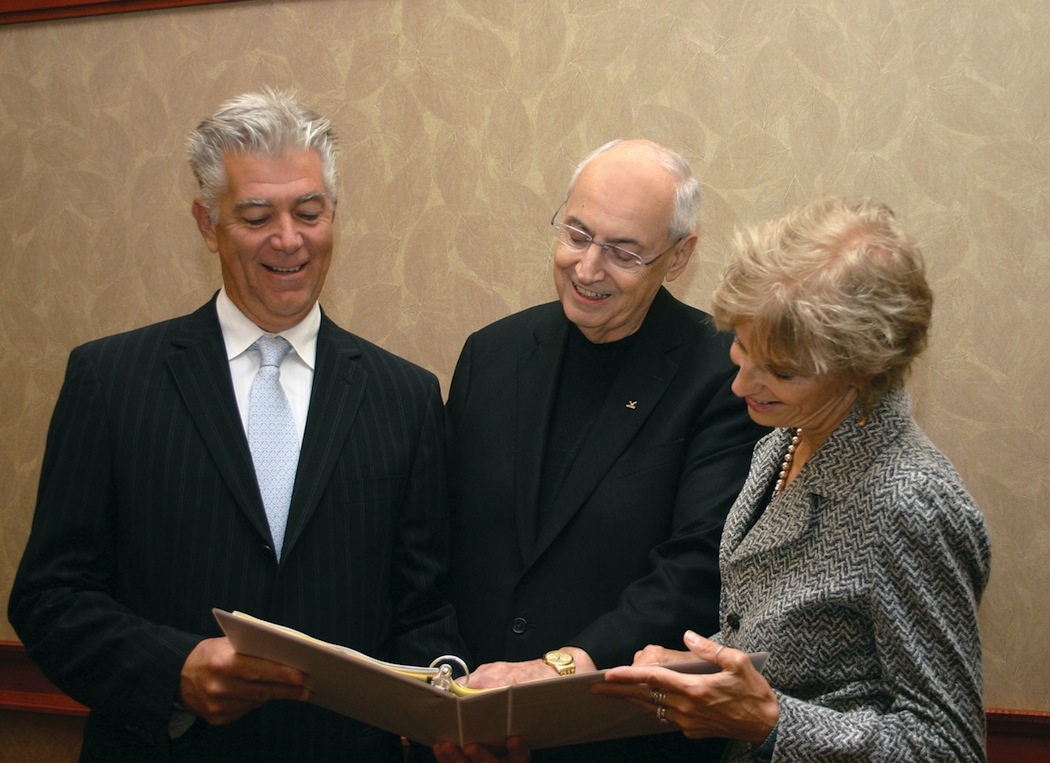 The Rev. Joseph L. Levesque, C.M., Niagara University president, reviews the menu for the President's Scholarship Dinner with chair-couple Christopher and Mary Ross, Class of 1982.