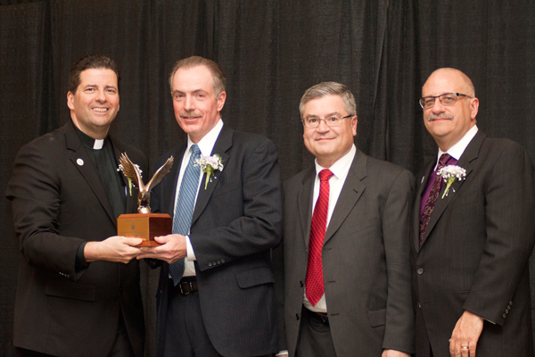 The Rev. James J. Maher, C.M., NU president, presents the Family Business of the Year Award to Reid Group CEO Paul Reid. Also pictured are Vince Agnello, director of NU's Family Business Center, and Dr. Shawn Daly, dean of the College of Business Administration.